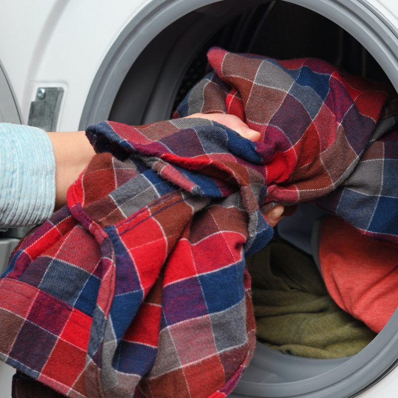 Woman puts clothes in washing machine